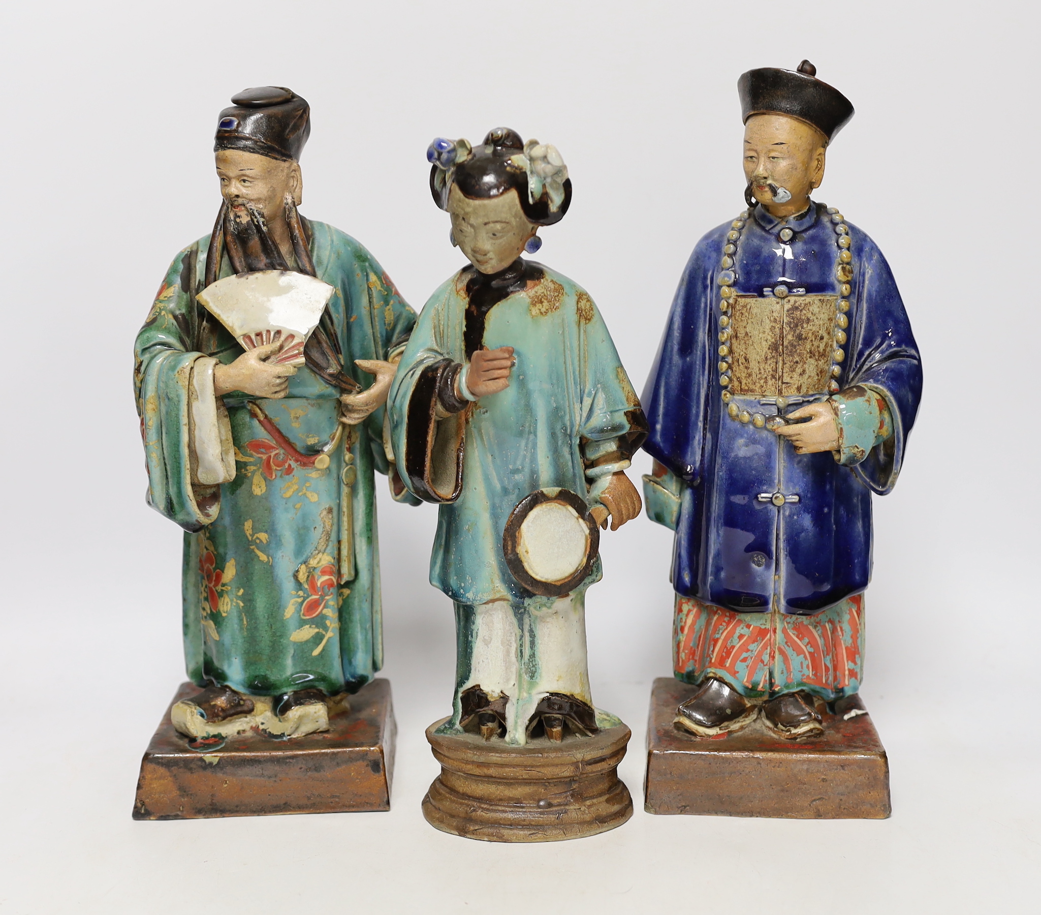A pair of large 19th century Chinese Shiwan or Guandong pottery figures of Mandarins, and a similar figure of a lady, tallest 32.5cm